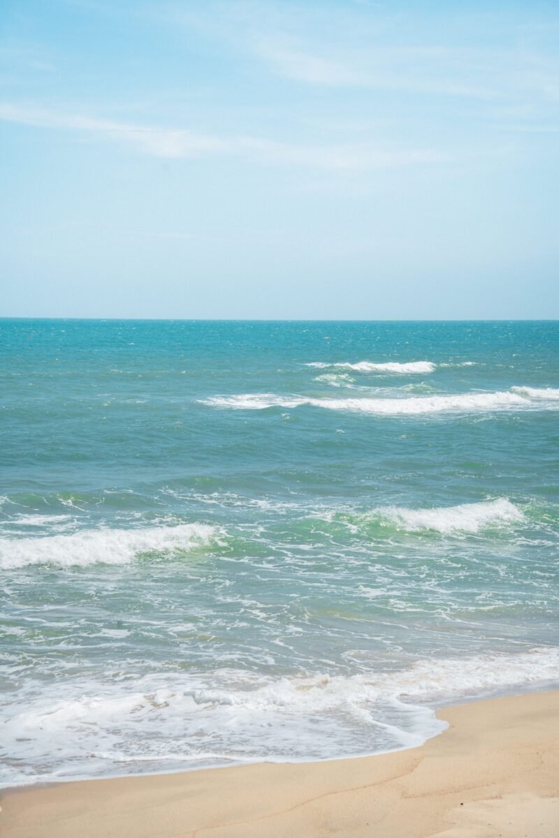 Serene beach scene with gentle waves and clear skies, perfect for relaxation and coastal vibes.