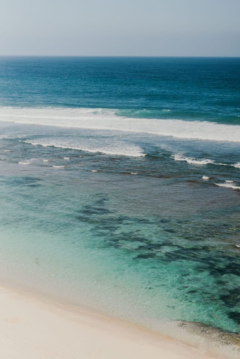 Explore the tranquil beauty of Bali's coastline with this aerial beach photograph showcasing clear waters and a serene horizon.